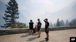 Hein and Teijs Reijnders try to see through the smoke at the famous Tunnel View vista in Yosemite National Park during its reopening day in California, Aug. 14, 2018. 