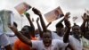 Des supporters brandissant des drapeaux soutenant Alassane Ouattara acclament le président de la Côte d'Ivoire lors de son discours au stade Félix Houphouët-Boigny, le 22 août 2020 à Abidjan, à l'occasion de son investiture par le RHDP. (Photo by Issouf SANOGO / AFP)