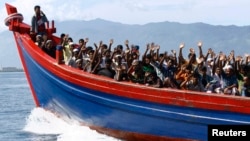 Ethnic Rohingya refugees from Myanmar wave as they are transported by a wooden boat to a temporary shelter in Krueng Raya in Aceh Besar, Indonesia, April 8, 2013.