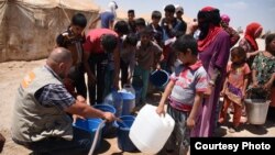 Norwegian Refugee Council staff provide drinking water for Iraqis from Fallujah at Amariyat Al Fallujah displacement camp. Photo: Karl Schembri/NRC