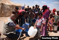 Nhân viên Hội đồng Người tị nạn Na Uy cung cấp nước uống cho thường dân lánh khỏi Fallujah tại một trại tị nạn. Hình: Karl Schembri/NRC