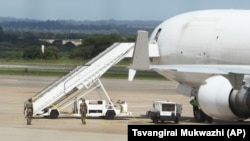 Zimbabwean armed soldiers patrol around a United States registered cargo plane at Harare International Airport in Harare, Zimbabwe, Monday, Feb,15.2016. Zimbabwean aviation authorities impounded a U.S.-registered cargo jet after a dead body later believed to be a stowaway and millions of South African rand were found on board, a senior official said Monday. (AP Photo/Tsvangirayi Mukwazhi)