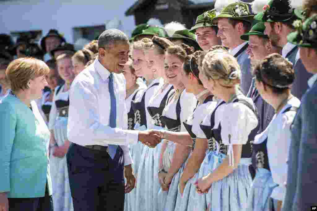 German Chancellor Angela Merkel, left, and U.S. President Barack Obama are welcomed by local residents in their traditional costumes during their visit in the village of Kruen, southern Germany, June 7, 2015.