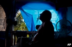 FILE - A man takes one of his 10 a day asthma treatments to help him breathe, inside his home still covered with a tarp a year after Hurricane Maria, in Naranjito, Puerto Rico, Sept. 9, 2018.