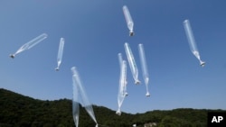 지난 2014년 10월 한국 경기도 파주에서 탈북자 단체 관계자들이 북한 김정은 정권을 비판하는 내용의 전단을 실은 풍선을 북으로 날려보내고 있다. (자료사진)