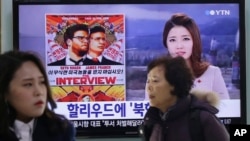 People pass a TV screen showing a news report on Sony Picture's 'The Interview,' at the Seoul Railway Station in South Korea.