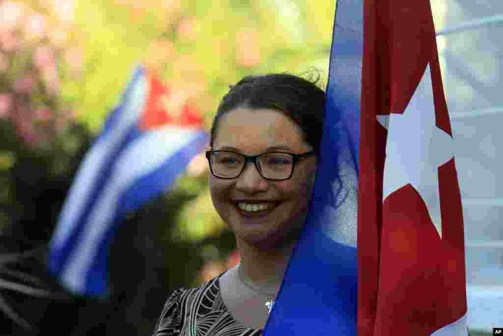 Seorang perempuan memegang bendera Kuba sementara merayakan pemulihan hubungan diplomatik antara Kuba dan AS, di halaman kedutaan besar Kuba di Santiago, Chile (17/12). (AP/Luis Hidalgo)