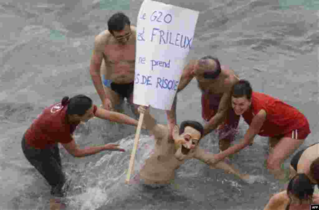 Anti-globalization activist wearing a mask representing French President Nicolas Sarkozy, demonstrates in the harbor of Nice, southeastern France, Wednesday, Nov. 2, 2011, during the G20 Summit of Cannes. The banner raeds "G20 is sensitive to the cold.