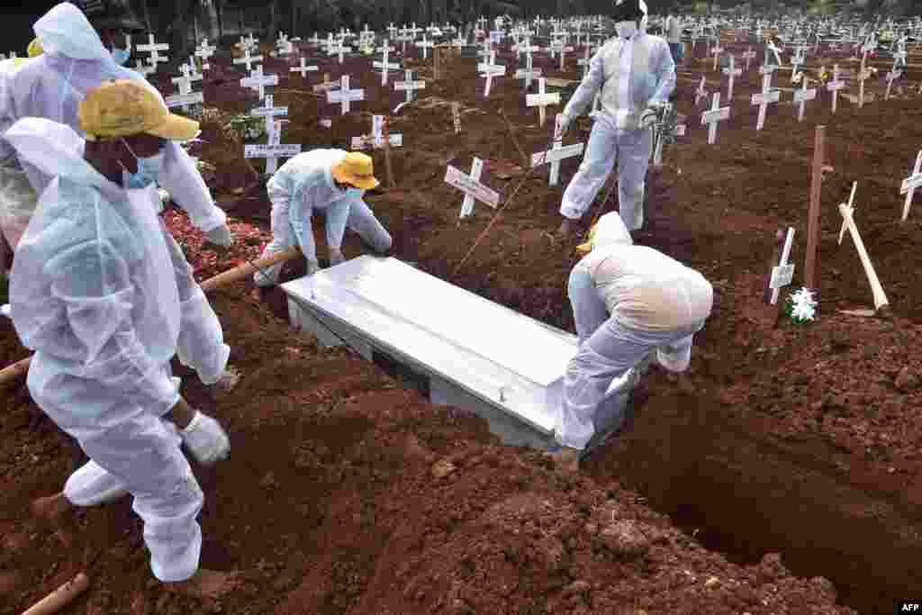 Grave diggers bury the coffin of a man who died from from COVID-19 at a cemetary in Bekasi, as Indonesia passed the grim milestone of over 100,000 COVID-19 deaths.