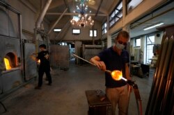 A glass-worker finishes a glass artistic creation in a factory in Murano island, Venice, Italy, Oct. 7, 2021.