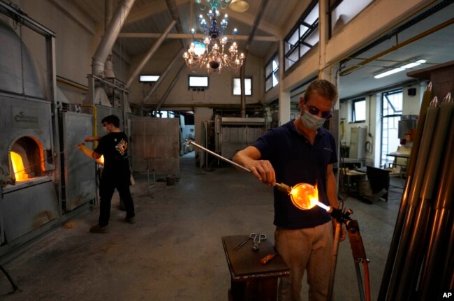 A glass-worker finishes a glass artistic creation in a factory in Murano island, Venice, Italy, Oct. 7, 2021.