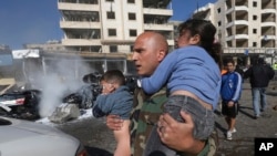 A Lebanese army soldier carries two injured children away from the site of an explosion near the Kuwaiti Embassy and Iran's cultural center, in the suburb of Beir Hassan, Beirut, Lebanon, Feb. 19, 2014. 