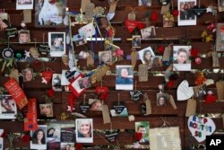 FILE - Photos and notes adorn a wall at the Las Vegas Community Healing Garden in Las Vegas, Oct. 16, 2017. The garden was built as a memorial for the victims of the mass shooting in Las Vegas.