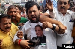 A demonstrator hits a poster of Pakistan’s Prime Minister Nawaz Sharif during a protest organized by India’s main opposition Congress party against Sunday's attack at an Indian army base camp in Kashmir's Uri in Jammu, India, Sept. 21, 2016.