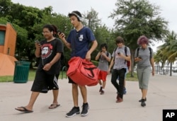 A group of Pokemon Go players check their smartphones as they look for Pokemon, Tuesday, July 12, 2016, at Bayfront Park in downtown Miami.