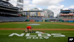 Un jardinero pinta un logo en la grama del Nationals Park en Washington D.C., el 5 de ocutbre de 2019. AP.