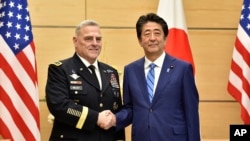 PM Jepang Shizo Abe (kanan) berjabat tangan dengan Ketua Gabungan Kepala Staf Angkatan Bersenjata AS, Jenderal Mark Milley di Tokyo, Jepang, 12 November 2019. 