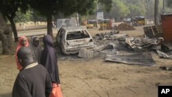 Children stand near the scene of an explosion in a mobile phone market in Potiskum, Nigeria, Jan. 12, 2015.