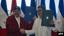 El presidente de Honduras Juan Orlando Hernández y el presidente de Nicaragua, Daniel Ortega, firman el Tratado de Integración del Bicentenario junto a la vicepresidenta de Nicaragua y la primera dama Rosario Murillo en Managua, el 27 de octubre de 2021.