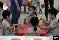 Pre-school children gather around a table inside their classroom as schools reopened in Singapore on June 2, 2020, as the city state eased its partial lockdown imposed to prevent the spread of COVID-19 in Singapore. (Photo by ROSLAN RAHMAN / AFP)