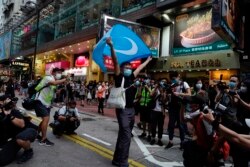 Seorang pengunjuk rasa mengibarkan bendera Uighur dalam aksi protes di Causeway Bay, Hong Kong, pada Hari Nasional China, Kamis, 1 Oktober 2020.