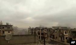 In this still image taken from video released by a Syrian activist Wednesday smoke rises in the distance alongside the sound of heavy bombardment in east Aleppo, as a cease-fire deal to evacuate the city’s residents begins to collapse. (Salah Ashkar via AP)