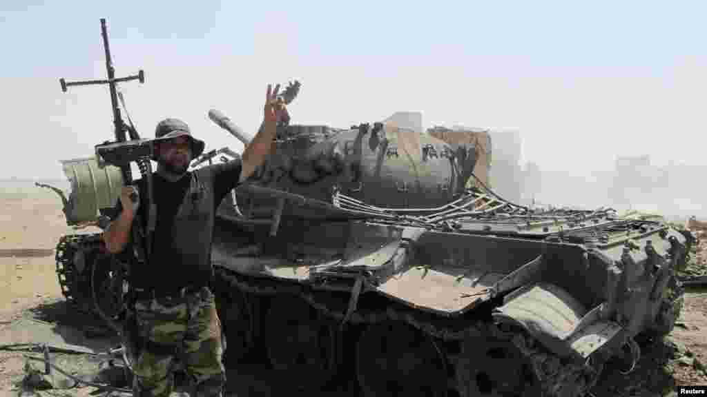 An Iraqi Shiite militia fighter flashes the victory sign, near the wreckage of a tank belonging to Islamic State militants, after breaking a long siege of Amerli by Islamic State militants, Sept. 2, 2014.