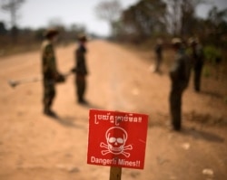 A sign warning of mines is placed on a road as Cambodian soldiers search for mines on the outskirts of Pailin, a former Khmer Rouge stronghold, in western Cambodia's Battambang province February 13, 2009. (Reuters)