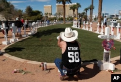 Jim Strickland, de Oroville, California, escribe un mensaje en una cruz en un monumento improvisado para las víctimas del tiroteo masivo del 1 de octubre de 2017 en Las Vegas, el domingo 30 de septiembre de 2018 en Las Vegas. "Necesitaba un cierre, así que tuve que volver", dijo Strickland, que estaba en el festival de música y regresó para el aniversario. (AP Photo / John Locher)