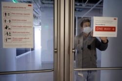 Kevin Gonzales, director of operations at the Rajen Kilachand Center for Integrated Life Sciences and Engineering, at Boston University, places safe distancing signage on glass doors on the school's campus, in Boston, Thursday, May 21, 2020. (AP Photo)