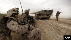 资料照片：美国海军陆战队在阿富汗马尔亚城边东北方一条交通要道巡逻时经过一辆正在清除土制炸弹的丹麦陆军豹2A5坦克。（2010年2月21日）