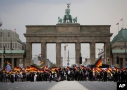 FILE - AfD supporters wave flags in front of the Brandenburg Gate in Berlin, Germany, May 27, 2018. The AfD swept into Parliament last year on a wave of anti-migrant sentiment.