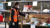 FILE - In this photo released by Xinhua News Agency, a staff member disinfects parcels at a community where a locally transmitted COVID-19 case was found, in Haidian district, Beijing, China, Jan. 18, 2022.
