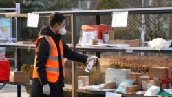 FILE - In this photo released by Xinhua News Agency, a staff member disinfects parcels at a community where a locally transmitted COVID-19 case was found, in Haidian district, Beijing, China, Jan. 18, 2022.
