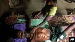 Mahata Onrao, a tea garden worker suffering from malnutrition, looks on while his wife Sukha Onrao attends to him at a rural health center in India (File Photo)