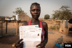 Grace Gaba holds her brother's refugee registration card in a camp for South Sudanese refugees in Aba, Democratic Republic of Congo. (J. Patinkin for VOA)