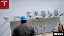 Labourers work on the exterior of a new Tesla showroom in Shanghai