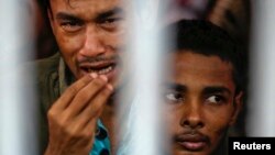 FILE - Rohingya people from Myanmar, who were rescued from human traffickers, react from inside a communal cell at Songkhla Immigration Detention Centre where they are kept near Thailand's border with Malaysia.