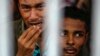 FILE - Rohingya people from Myanmar, who were rescued from human traffickers, react from inside a communal cell at Songkhla Immigration Detention Centre where they are kept near Thailand's border with Malaysia.