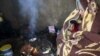 A Palestinian woman and her daughter, wrapped with a blanket, sit by a fire as they make tea inside their dwelling during a winter storm in Khan Younis in the southern Gaza Strip January 25, 2016. 