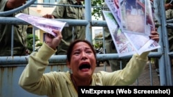 Bà Huỳnh Thị Hồng Loan kêu khóc với hình ảnh và giấy tờ khiếu kiện trên tay.