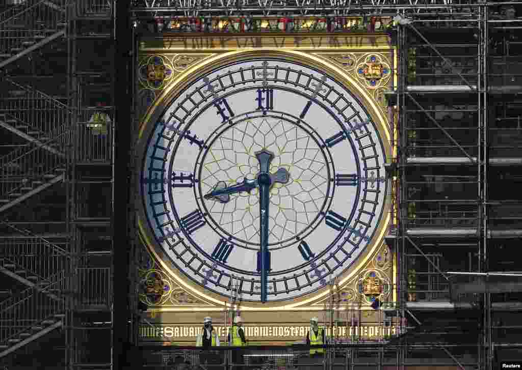 Workers stand on scaffolding underneath one of the clock faces on the Elizabeth Tower - more commonly known as Big Ben - as hands and dials are seen restored to the original Prussian blue coloring, whilst renovation works continue at the Houses of Parliament in London.