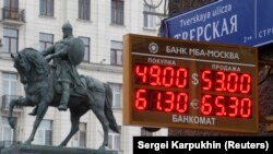Sebuah layar yang dipasang di depan Monumen Pangeran Yury Dolgoruky di Moskow, menunjukkan nilai tukar mata uang Rusia dengan mata uang asing, pada 1 Desember 2014. (Foto: Reuters/Sergei Karpukhin)