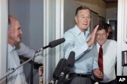 President George H.W. Bush talks with reporters en route to Washington D.C. in 1991. At right is John Sununu, his chief of staff, just before he was replaced.