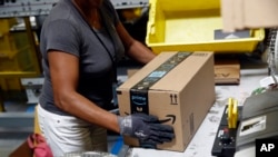 FILE - An Amazon employee applies tape to a package before shipment at an Amazon fulfillment center in Baltimore, Maryland, Aug. 3, 2017. 