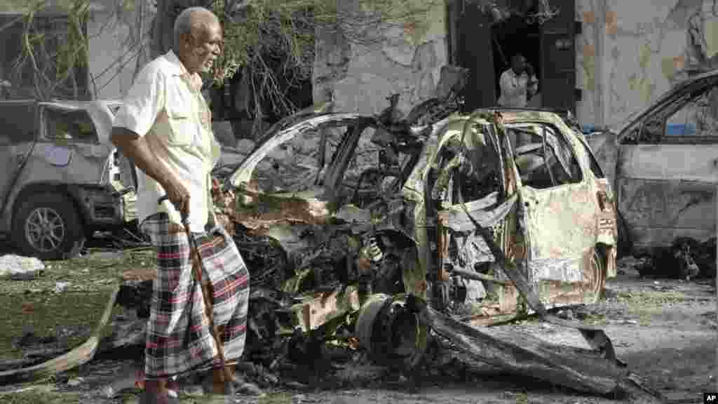 Un passant devant une voiture calcinée après l&#39;explosion à l&#39;hôtel de Mogadiscio, 2 juin 2016.