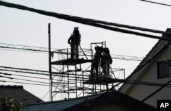 TV cameramen are seen on top of a nearby house in front of Tokyo Detention Center, where former Nissan chairman Carlos Ghosn is detained, March 5, 2019, in Tokyo.
