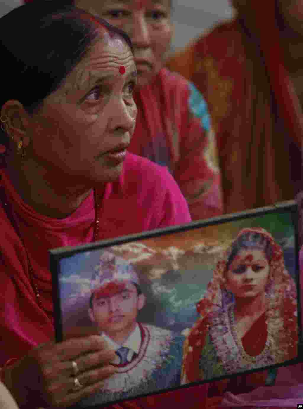 Indian woman Padma holds a photograph showing her son Bharat and daughter in law Partima with whom she has not been able to establish contact after Saturday&#39;s earthquake in Nepal, during a prayer ceremony for the earthquake affected at a Hindu temple in Jammu, India.