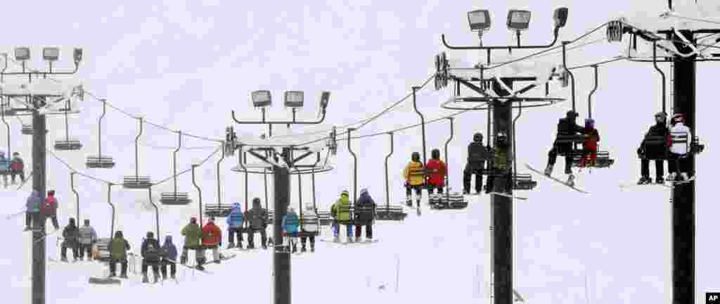 Skiers and snowboarders ride a lift up a mountain at Snoqualmie Pass, Washington, USA. A weather pattern that could be associated with El Nino has turned winter upside-down across the U.S. during a week of heavy holiday travel, bringing spring-like warmth to the Northeast, a risk of tornadoes in the South and so much snow in parts of the West that there are concerns about avalanches.