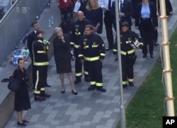 Britain's Prime Minister Theresa May, center, speaks to firefighters after arriving at Grenfield Tower in London, June 15, 2017, following a deadly fire in the apartment block.